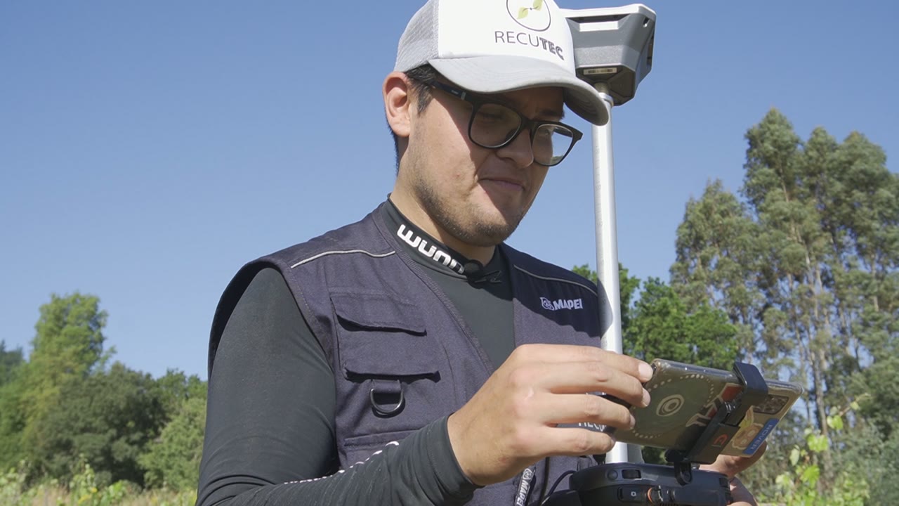 Operador de Recutec con el control del dron en la mano, junto al bastón del GPS